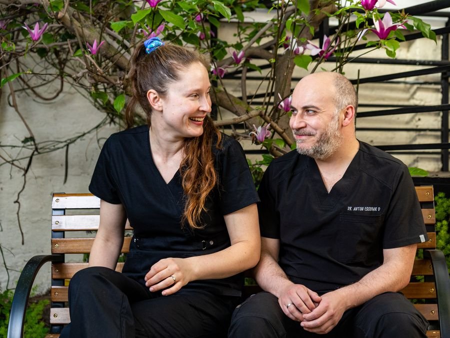Anton y Pierina, los médicos fundadores, sentados en la banca del jardín bajo la magnolia en flor, mirándose y sonriendo.
