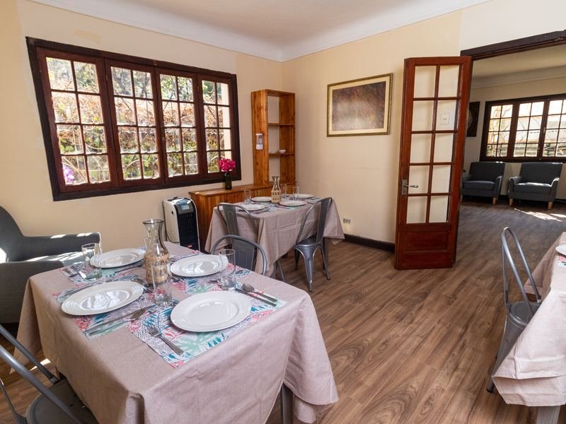 Comedor con mesas puestas con mantel y vajilla.